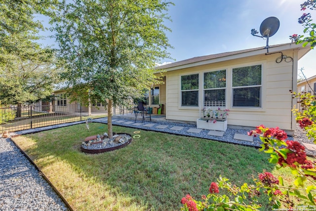 rear view of house featuring a yard, a patio area, and fence