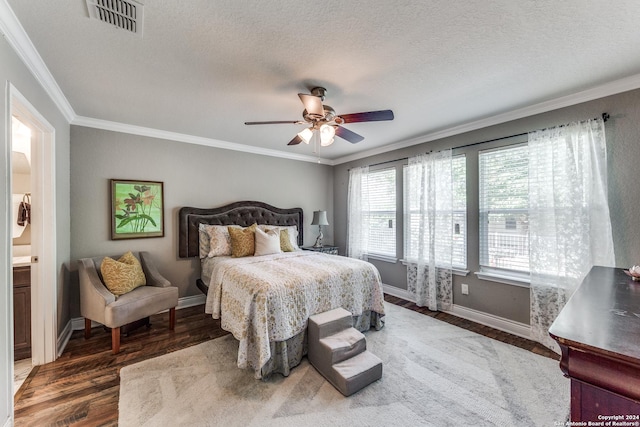 bedroom with a textured ceiling, wood finished floors, visible vents, baseboards, and ornamental molding