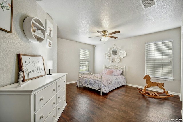 bedroom with dark wood-style flooring, visible vents, a textured ceiling, and baseboards