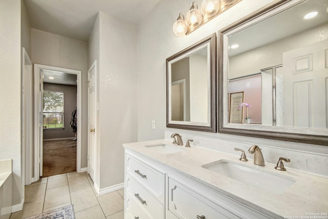 full bathroom with double vanity, tile patterned flooring, a sink, and baseboards