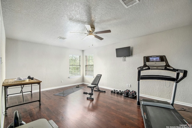 workout area featuring ceiling fan, a textured wall, wood finished floors, and visible vents