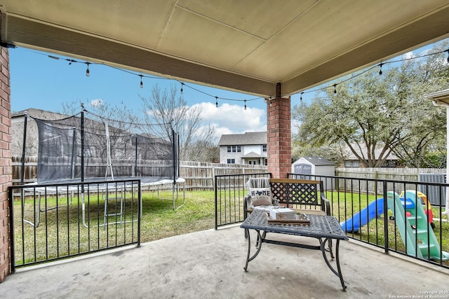 view of patio / terrace with a storage unit, a trampoline, an outdoor structure, and a fenced backyard