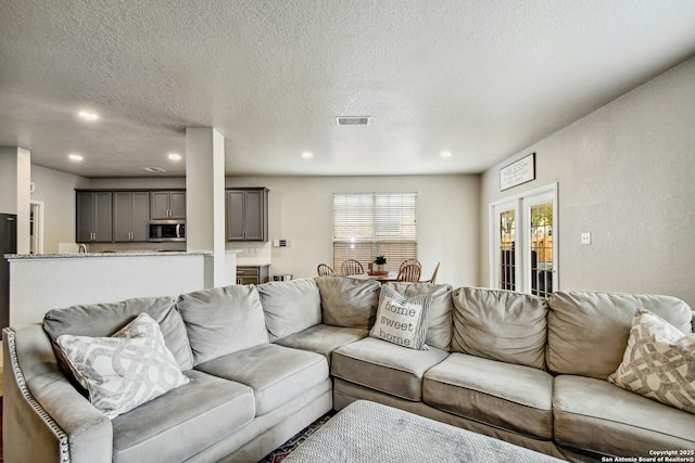 living room featuring visible vents, a textured ceiling, and recessed lighting