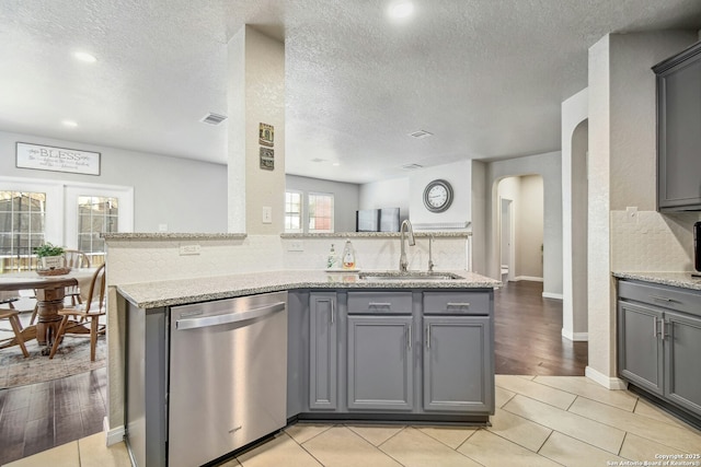 kitchen featuring arched walkways, a sink, visible vents, stainless steel dishwasher, and gray cabinets