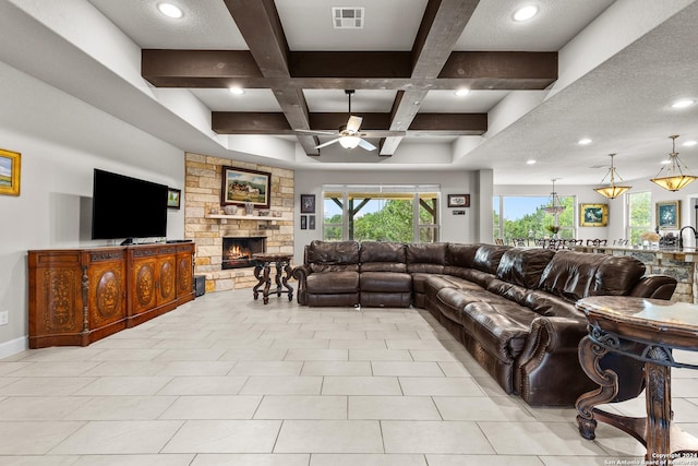 living room featuring visible vents, coffered ceiling, a ceiling fan, beamed ceiling, and a stone fireplace