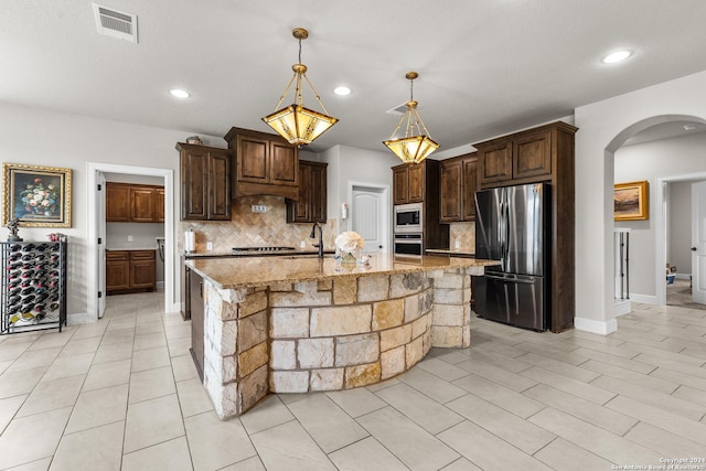 kitchen with dark brown cabinetry, visible vents, appliances with stainless steel finishes, backsplash, and a sink