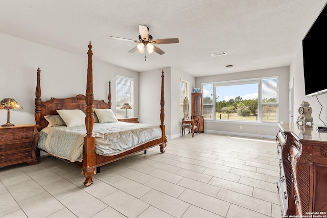 bedroom featuring a textured ceiling, light tile patterned floors, a ceiling fan, visible vents, and baseboards