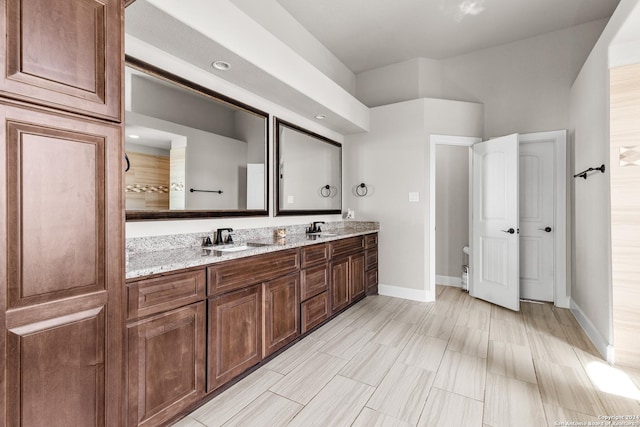 full bath featuring double vanity, baseboards, and a sink