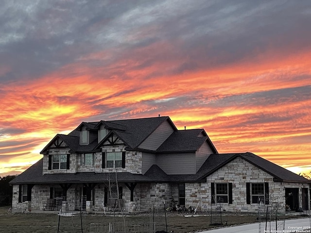 view of front facade with a shingled roof and stone siding