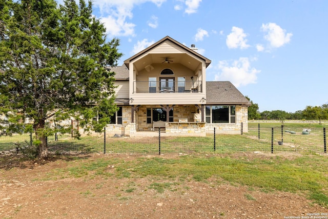 rear view of property with a balcony, stone siding, ceiling fan, fence, and a patio area