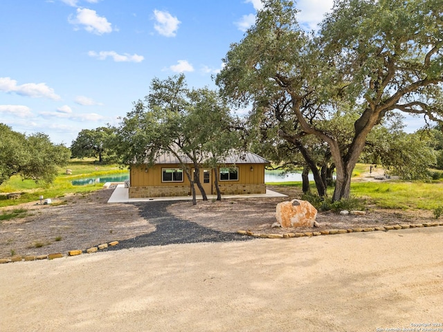 view of front of home featuring driveway, a water view, and stone siding