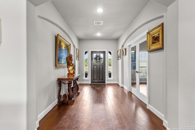 entryway featuring baseboards, visible vents, dark wood finished floors, and a textured ceiling