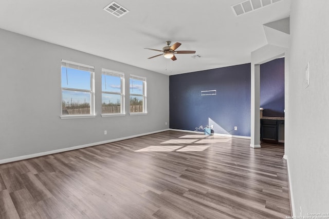 empty room featuring baseboards, wood finished floors, visible vents, and a ceiling fan