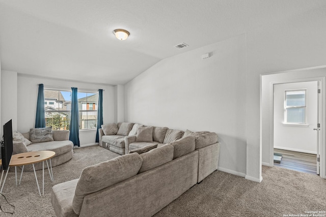 carpeted living room with lofted ceiling, visible vents, and baseboards