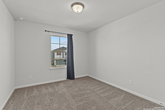 spare room featuring carpet floors and baseboards