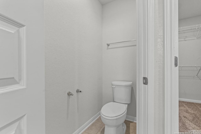 bathroom featuring a spacious closet, tile patterned flooring, toilet, and baseboards