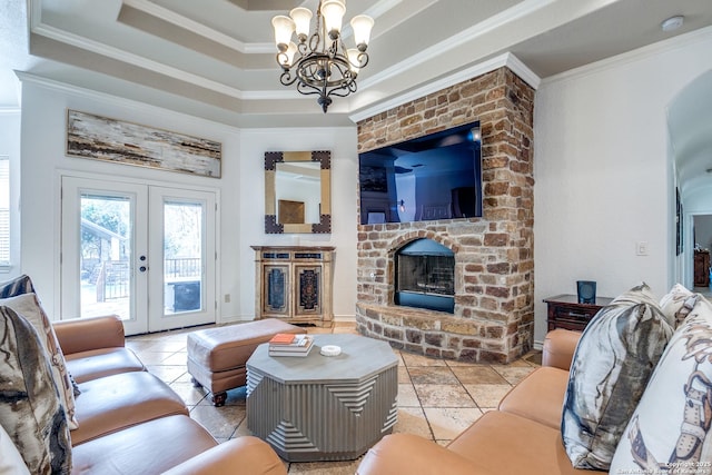 living room with a tray ceiling, french doors, crown molding, a fireplace, and an inviting chandelier