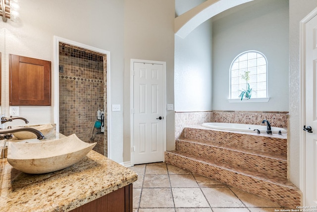 full bathroom with a garden tub, vanity, and stone tile floors