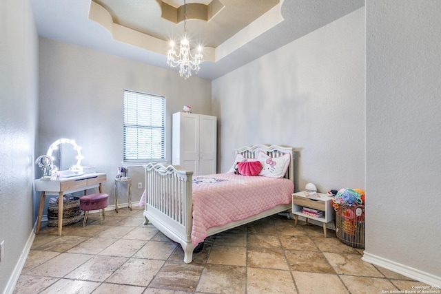 bedroom with a notable chandelier, a raised ceiling, stone tile flooring, and baseboards