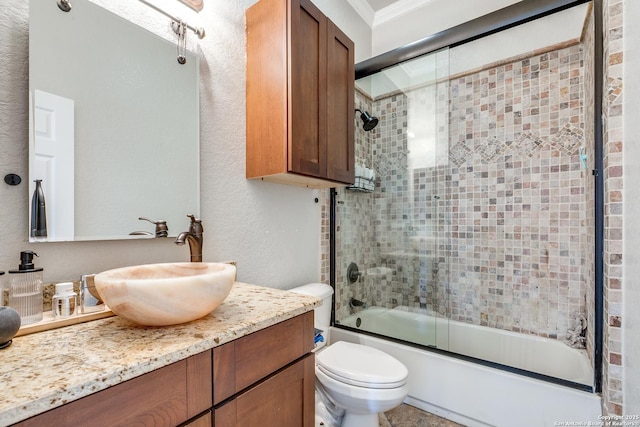 full bath featuring a textured wall, toilet, enclosed tub / shower combo, crown molding, and vanity