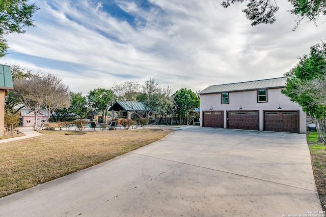 exterior space with metal roof, a garage, a lawn, stucco siding, and a standing seam roof