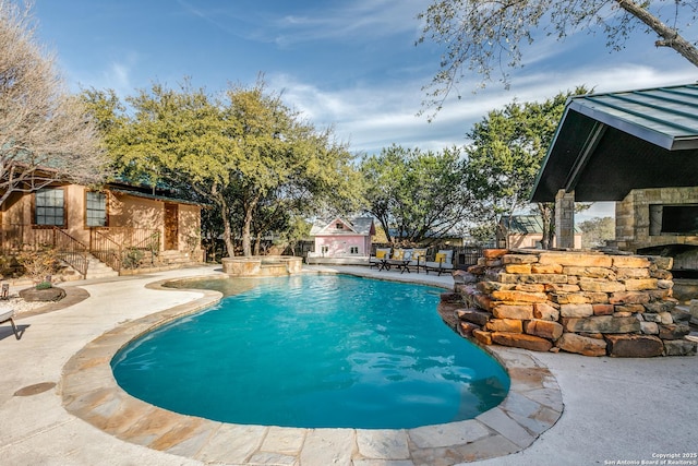 view of swimming pool featuring a pool with connected hot tub, an outdoor stone fireplace, and a patio