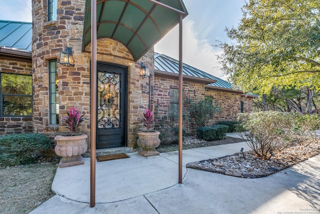 property entrance with a standing seam roof, stone siding, and metal roof