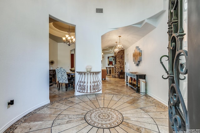 entryway with an inviting chandelier, visible vents, baseboards, and arched walkways