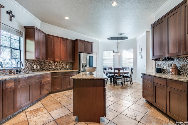 kitchen with a center island, crown molding, visible vents, a sink, and stainless steel fridge