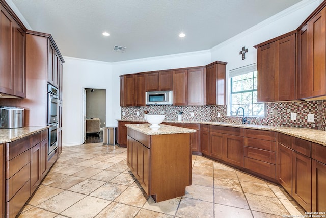 kitchen with tasteful backsplash, a kitchen island, ornamental molding, and stainless steel appliances