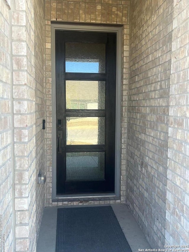 view of exterior entry featuring brick siding