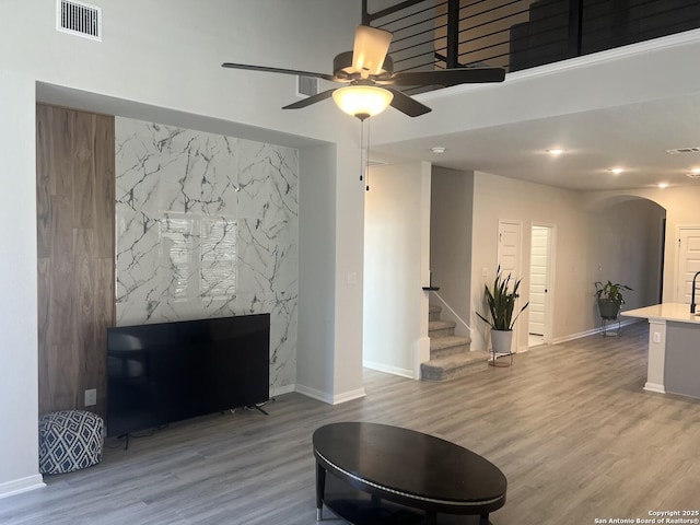 living room featuring arched walkways, wood finished floors, visible vents, and stairs