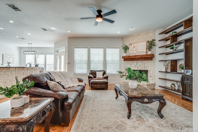 living area featuring a healthy amount of sunlight, a fireplace, visible vents, and wood finished floors