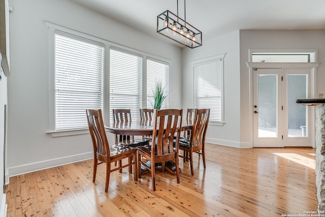 dining area with light wood-style floors, baseboards, and an inviting chandelier