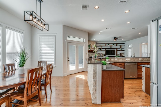 kitchen with dark countertops, a wealth of natural light, light wood-style flooring, and dishwasher