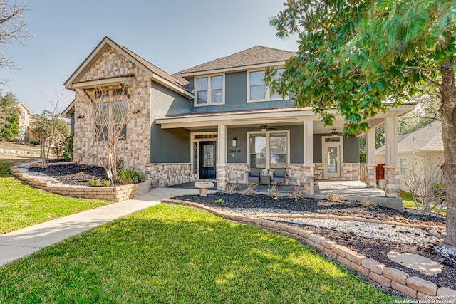 view of front of property with covered porch, stone siding, a front lawn, and stucco siding