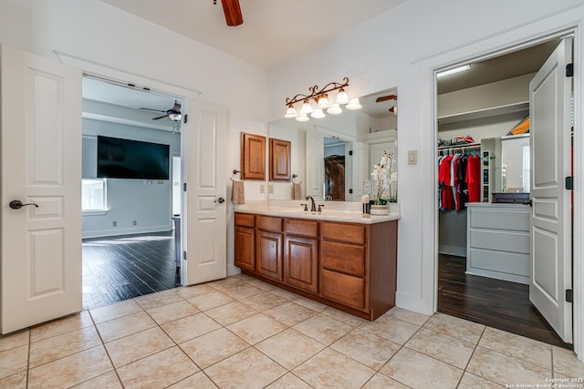 bathroom with tile patterned flooring, a spacious closet, a ceiling fan, and vanity