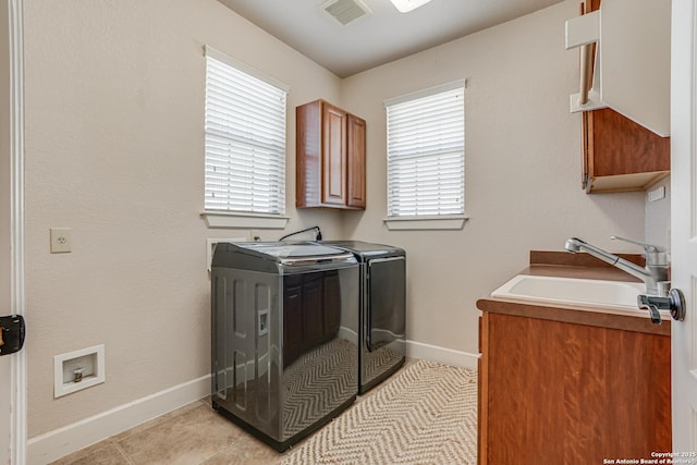 clothes washing area featuring a sink, visible vents, baseboards, cabinet space, and washer and clothes dryer