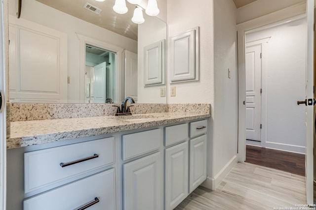 bathroom with visible vents, vanity, baseboards, and wood finished floors