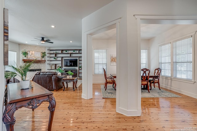 entryway featuring baseboards, ceiling fan, light wood-type flooring, a fireplace, and recessed lighting