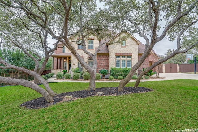 traditional-style home featuring stone siding, a shingled roof, a front yard, and brick siding