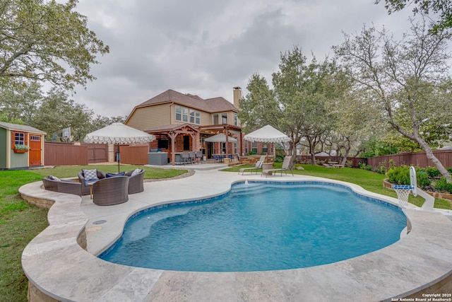 view of pool with a patio, a fenced backyard, an outdoor hangout area, an outdoor structure, and a shed