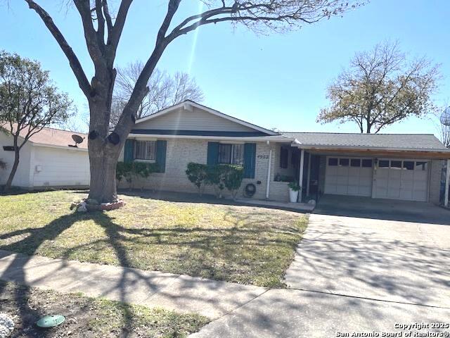 ranch-style house with a garage, brick siding, driveway, and a front lawn