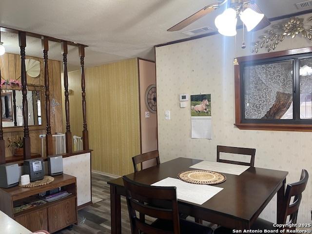 dining space with a ceiling fan, wood finished floors, visible vents, and wallpapered walls