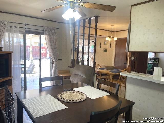 dining space featuring ceiling fan with notable chandelier