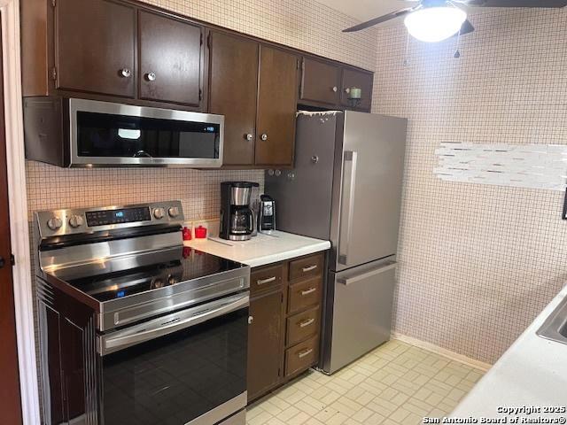 kitchen featuring dark brown cabinetry, a ceiling fan, light countertops, appliances with stainless steel finishes, and backsplash