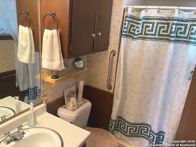 bathroom featuring toilet, curtained shower, vanity, and wallpapered walls