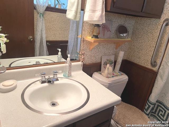 full bathroom featuring vanity, toilet, and wallpapered walls