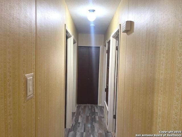 corridor with a textured ceiling and wood finished floors