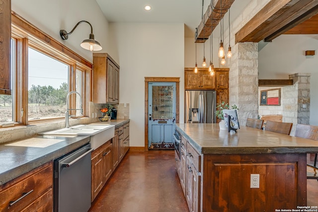 kitchen with stainless steel appliances, a sink, backsplash, brown cabinets, and finished concrete floors